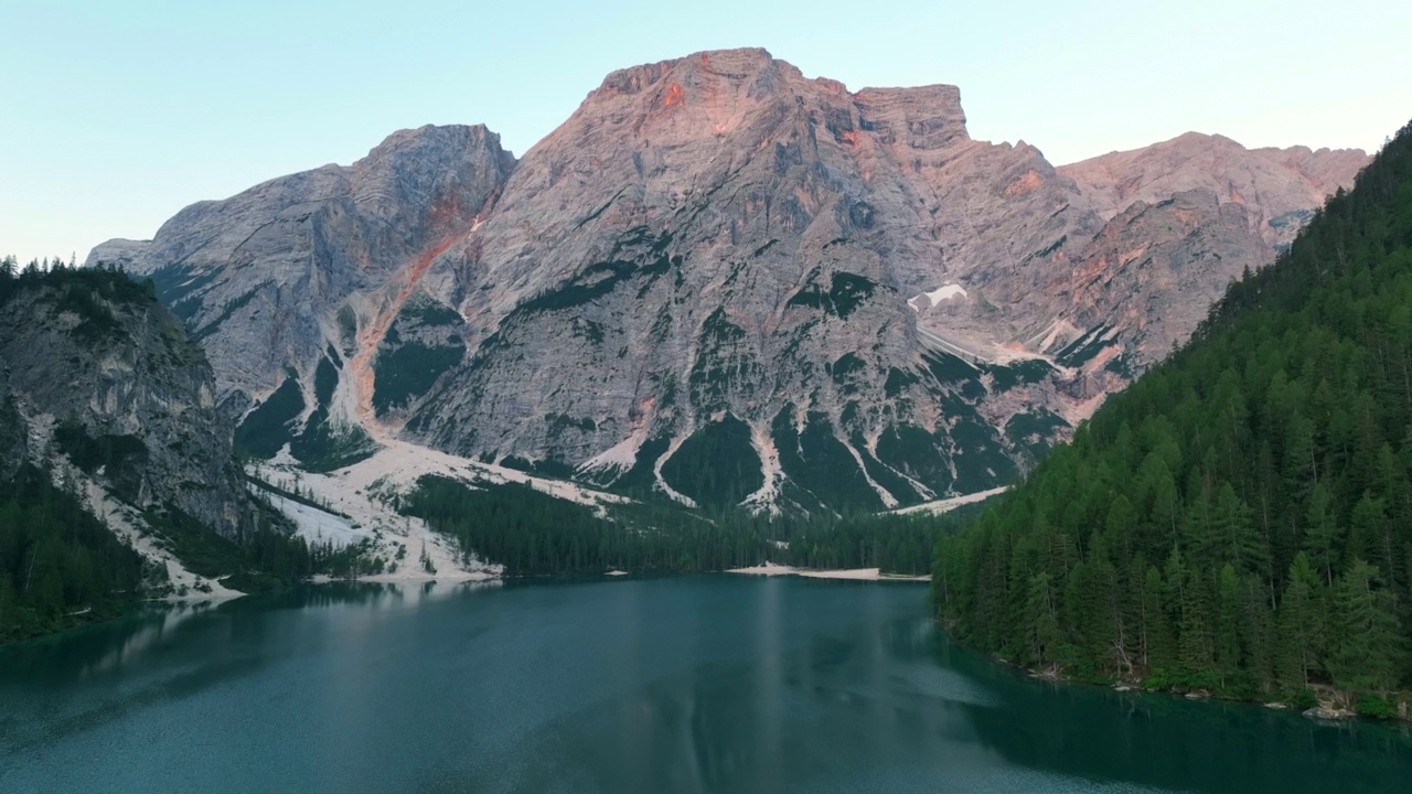 无人机查看最美丽的拉戈迪布雷斯的日出场景，也被称为Pragser Wildsee。白云石山脉,意大利。飞出碧绿平静的水面，船在生涩。视频素材