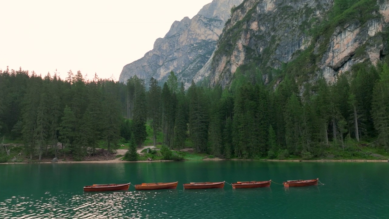 无人机查看最美丽的拉戈迪布雷斯的日出场景，也被称为Pragser Wildsee。白云石山脉,意大利。飞出碧绿平静的水面，船在生涩。视频素材