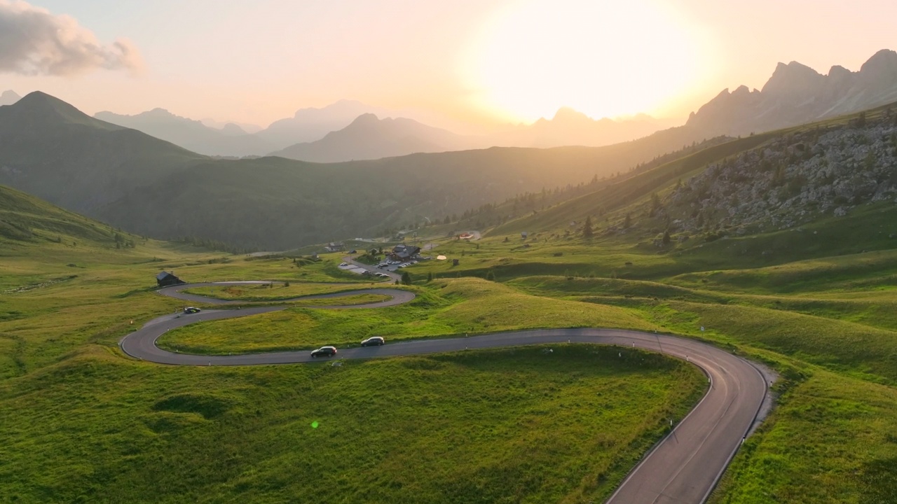 全景无人机飞行视频环绕交通道路绿山与美丽的日落景象白云石阿尔卑斯山脉的夏季景观。美丽的桥山口- 2236米的山口，位于意大利贝卢诺省视频素材