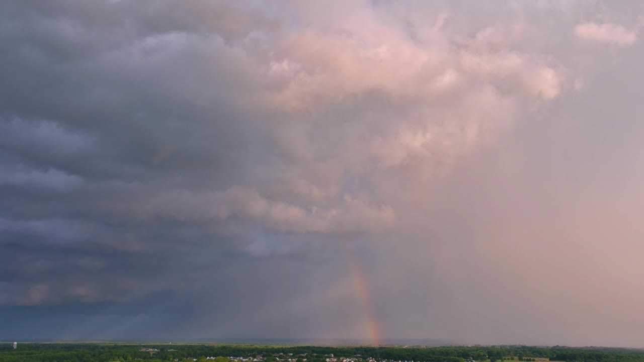 当一场严重的雷雨发生时，一道明亮的彩虹出现在天空中，映衬着美丽的风景。视频素材