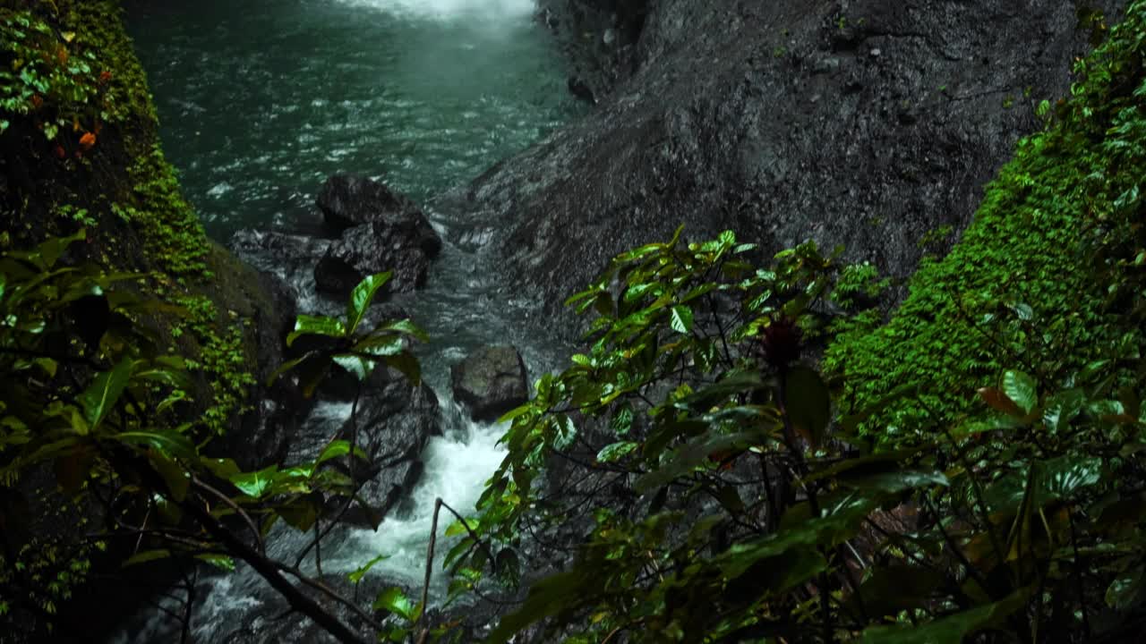 瀑布与岩石之间的热带丛林与绿色植物和树木和水下降视频素材