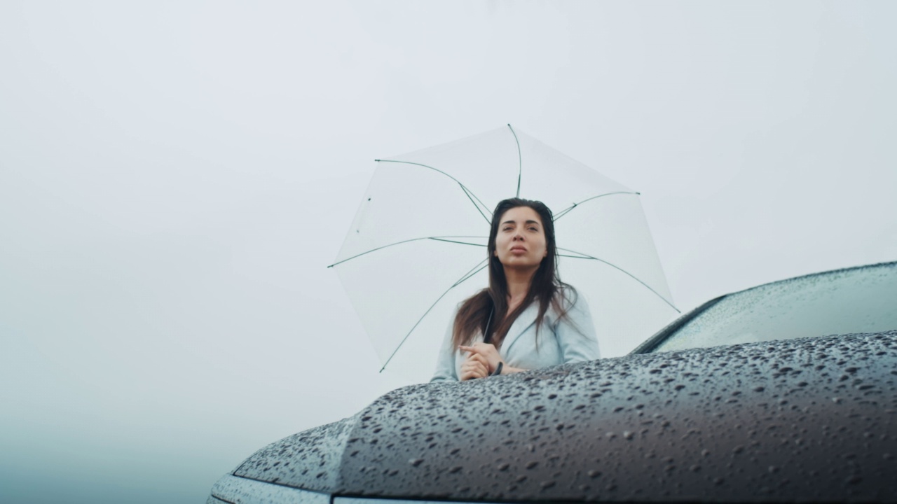 一个悲伤的亚美尼亚女人撑着伞在雨中行走。她喜欢这种天气。视频素材