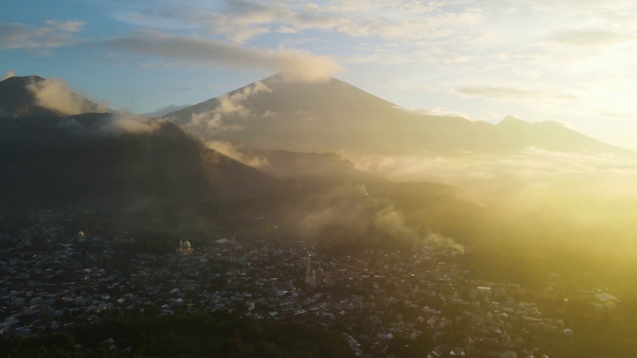 雾蒙蒙的村庄和稻田，龙目岛的背景是雄伟的林贾尼火山，位于森巴伦村。4 k鸟瞰图视频下载