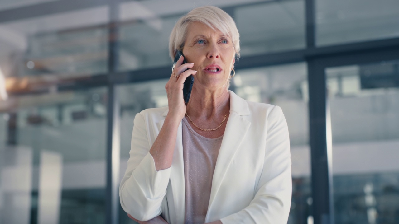 一位成熟的女商人站在办公室里讲电话。自信的女性企业家和领导者在电话中进行商业交易或安排与客户或同事的会议视频素材