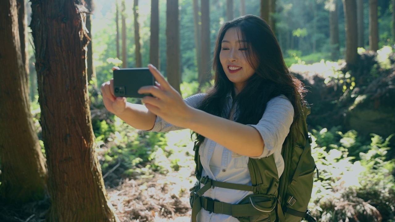 年轻女子自拍与手机徒步在森林视频素材