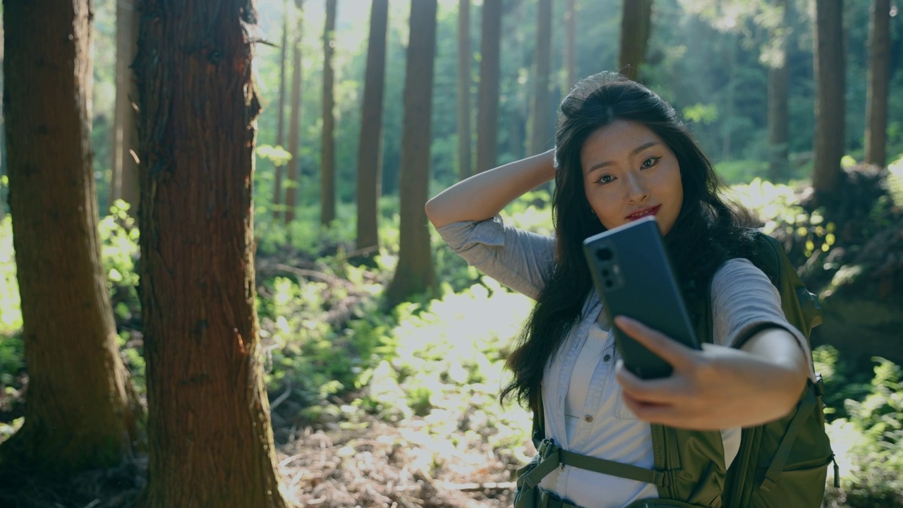 年轻女子自拍与手机徒步在森林视频素材