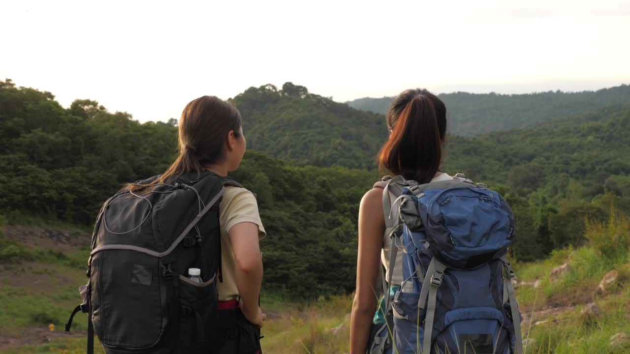 两个年轻的女徒步旅行者在美丽的大自然中自豪地到达了目的地。视频素材