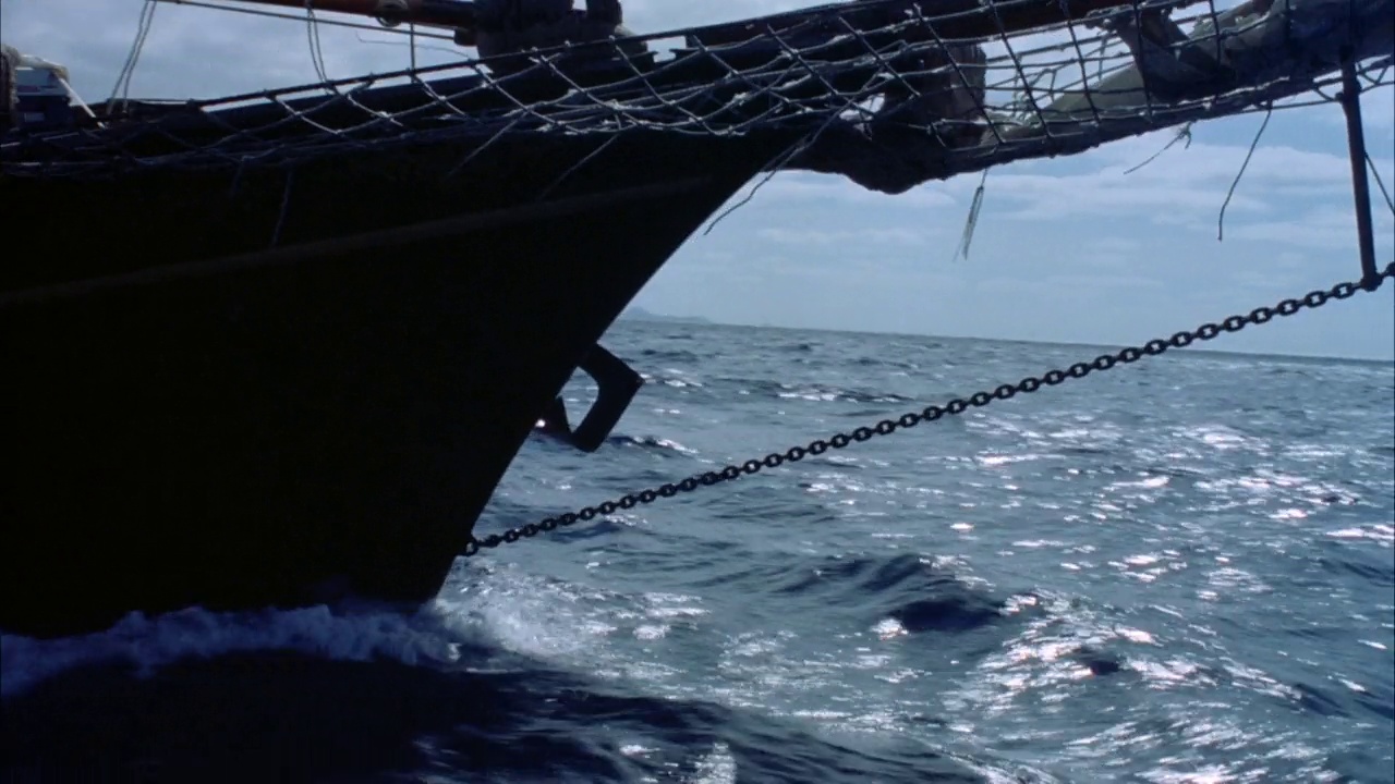 船首夹角。看见船头斜桅在前面到右边，渔网和铁链。远处背景中的海洋地平线。人坐在弓的边缘。小电流视频素材