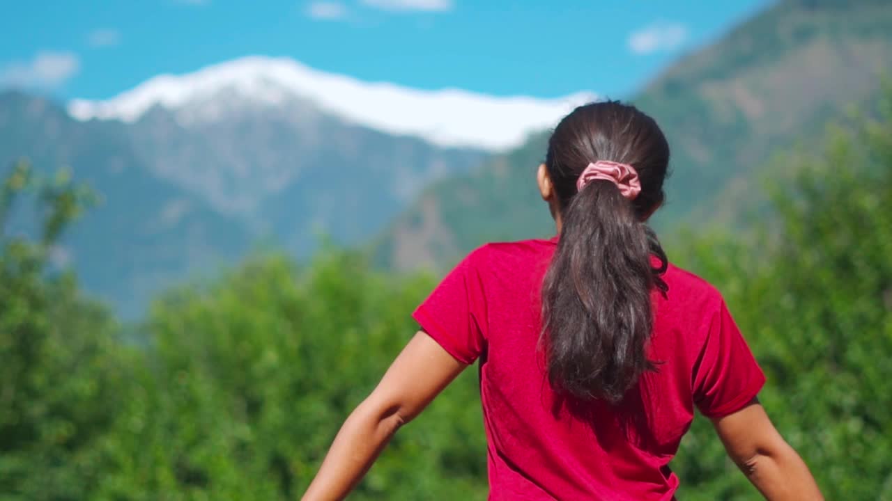 十几岁的印度女孩旅行者的后视图看雪山。印度喜马偕尔邦马那利的游客。这个女孩喜欢待在山里。露营。休闲。视频素材