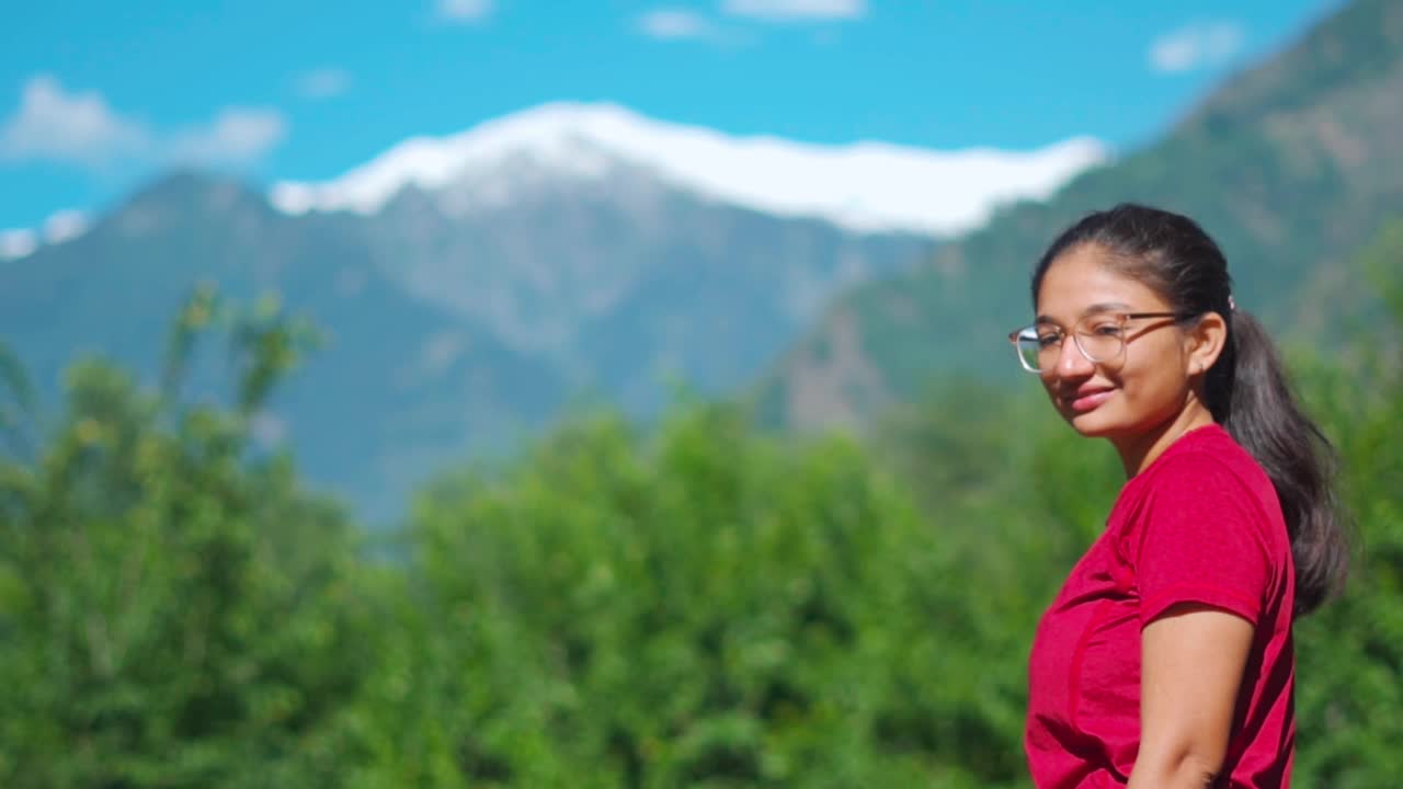 美丽的印度少女的肖像享受夏天的阳光在背景的雪山在马那利，喜马偕尔邦，印度。女性游客在假期放松身心视频素材