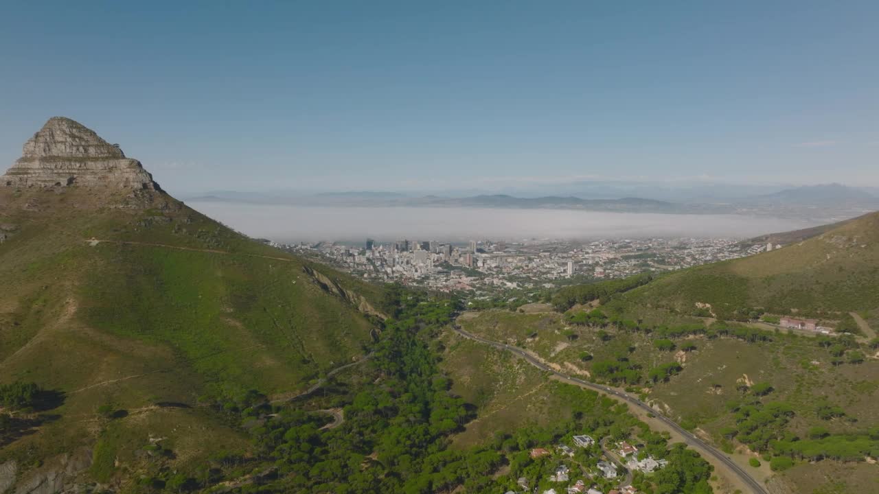 山口上通往大城市的繁忙道路的空中下降镜头。狮子头山高耸于周围景观之上。开普敦，南非视频素材