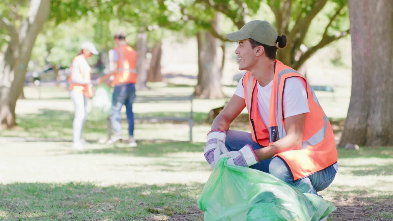 快乐的年轻人清洁公园在一个生态友好的社区。负责任的委员会工作人员、积极分子或志愿者收集垃圾和垃圾，以建立一个可持续、清洁和安全的环境视频素材