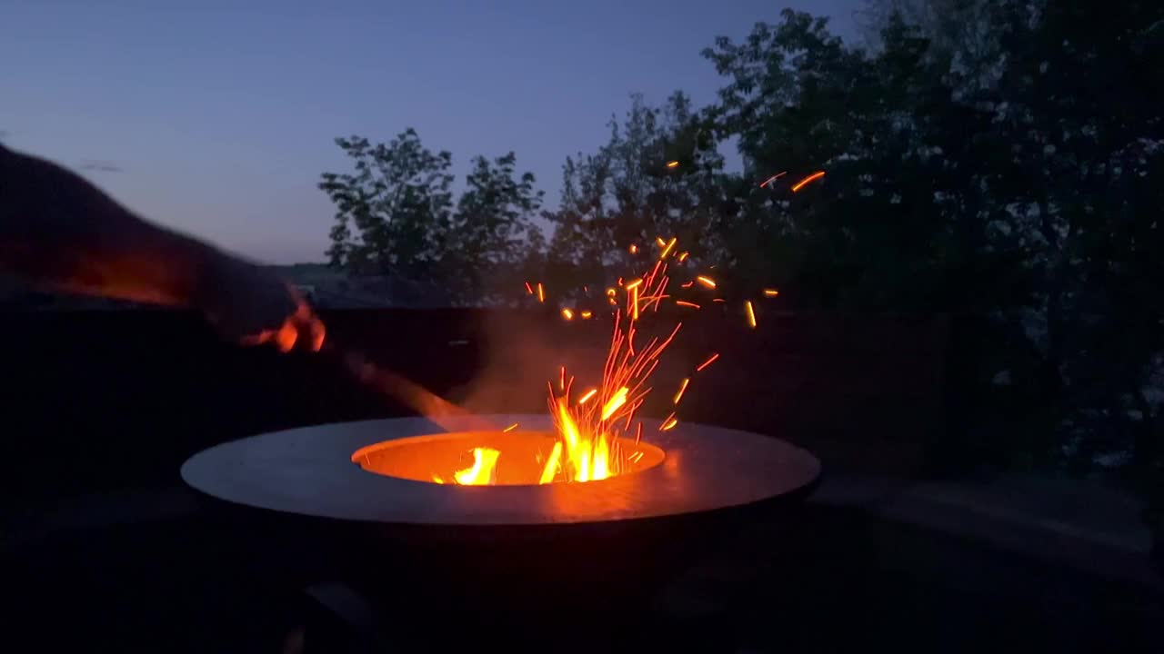 晚上森林里燃起了篝火。人闪电出火，火焰出火。夜晚的篝火，原木，火花飞舞。壁炉自然。4 k视频素材