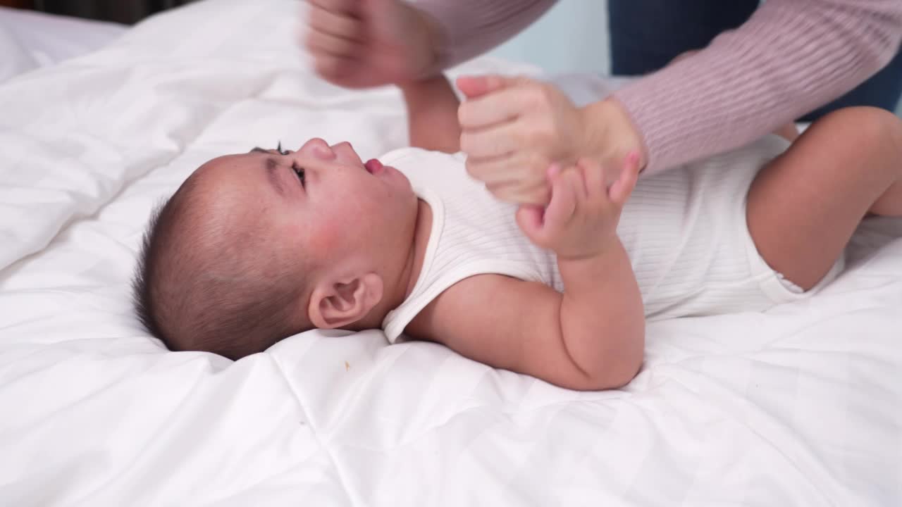 微笑的新生婴儿或可爱的小躺在家里白色的床上。婴儿儿童肖像快乐理念，健康育儿晨。视频素材