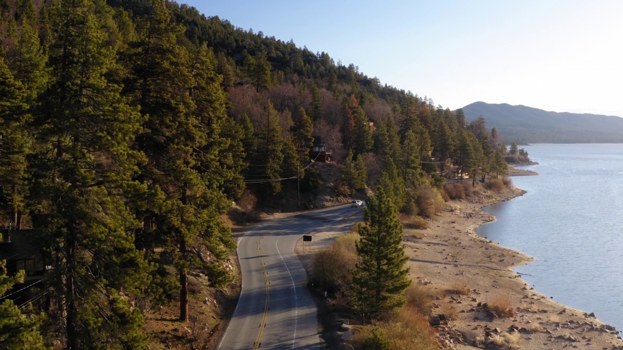 空中:汽车在道路上移动的森林树木，无人机飞行向前在海上海岸线-大熊，加州视频素材