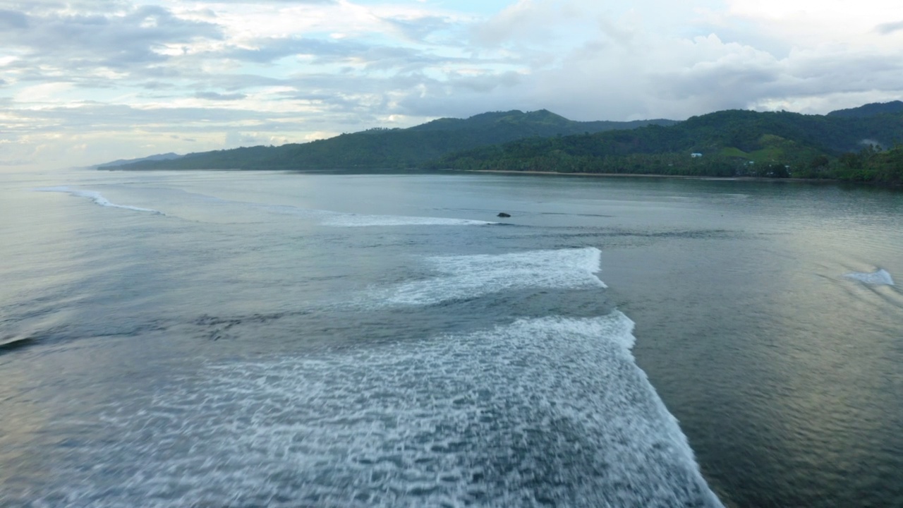 在多云的天空下拍摄岛屿的空中美景，无人机向前飞行在波涛汹涌的海上-苏瓦，斐济视频素材