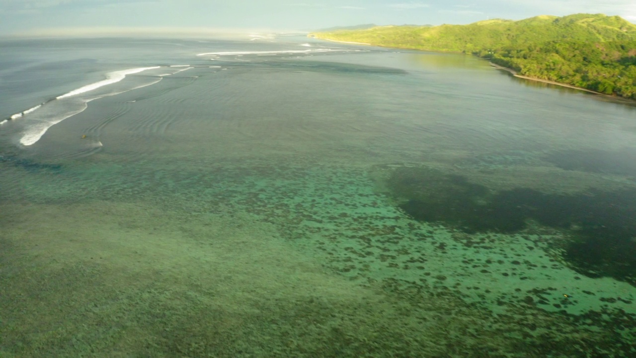 空中平移风景拍摄的绿岛，无人机在波浪海上向后飞行-苏瓦，斐济视频素材