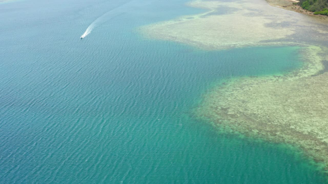 空中平移的美丽镜头的快艇移动的绿地，无人机飞越波纹海洋-苏瓦，斐济视频素材