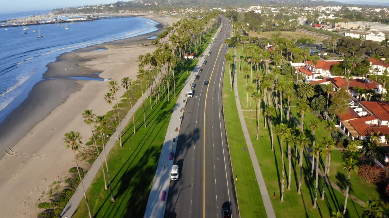 航拍前进的汽车移动在道路上的城市海滩在阳光明媚的日子-圣巴巴拉，加利福尼亚视频素材