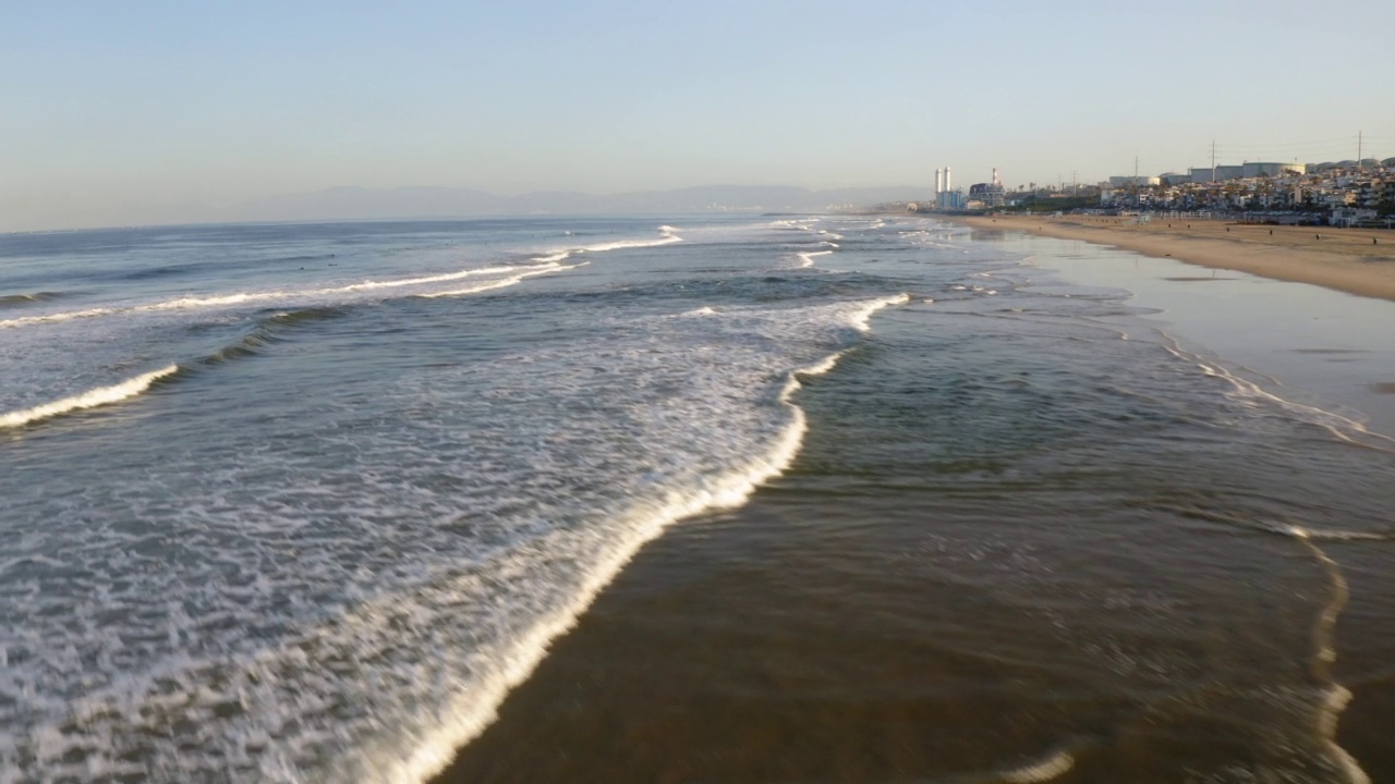 航拍的人与冲浪板在城市的海滩，无人机飞行向前在波浪海-曼哈顿海滩，加州视频素材