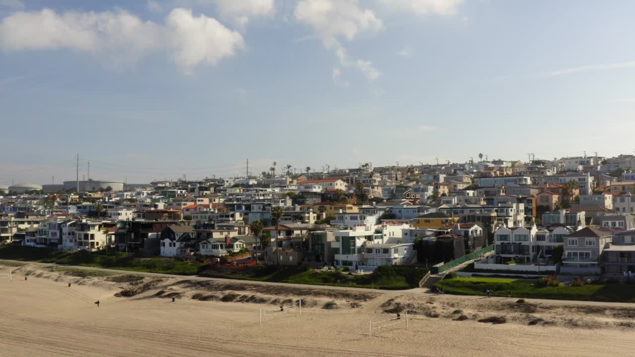 空中拍摄的人骑自行车在道路上的住宅平房，无人机飞行向前越过海滩-曼哈顿海滩，加州视频素材