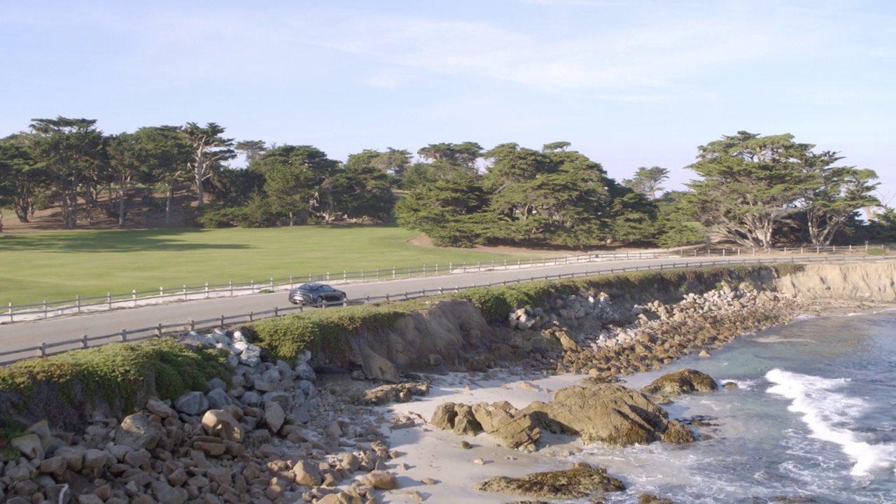 空中前进拍摄汽车移动在道路上的绿色景观，无人机飞行向前在海上-德尔蒙特森林，加州视频素材