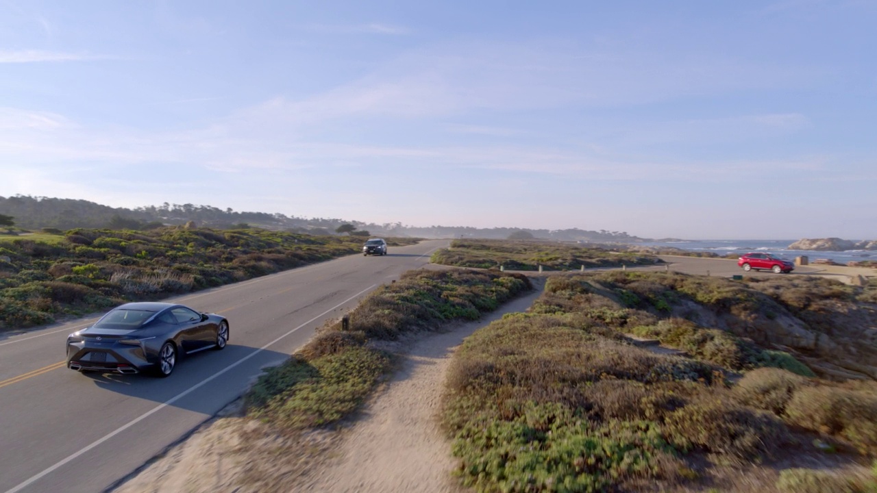 平移拍摄车辆移动在道路上的景观在阳光明媚的一天-德尔蒙特森林，加州视频素材