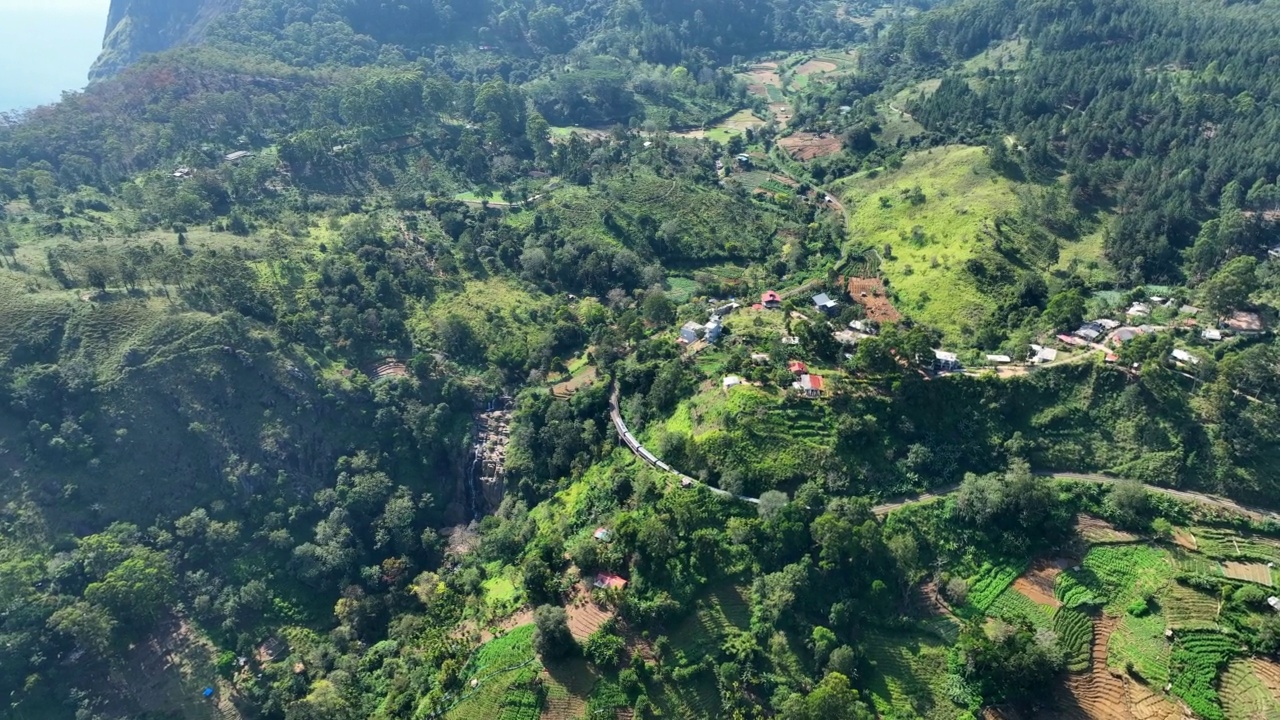 空中平移风景拍摄的火车移动在绿色的山，无人机在晴朗的日子飞行-埃拉，斯里兰卡视频素材