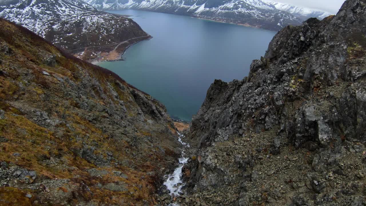 在白雪皑皑的山脉中空中欣赏美丽的海景，无人机在瀑布上向下飞行-特罗姆瑟，挪威视频素材