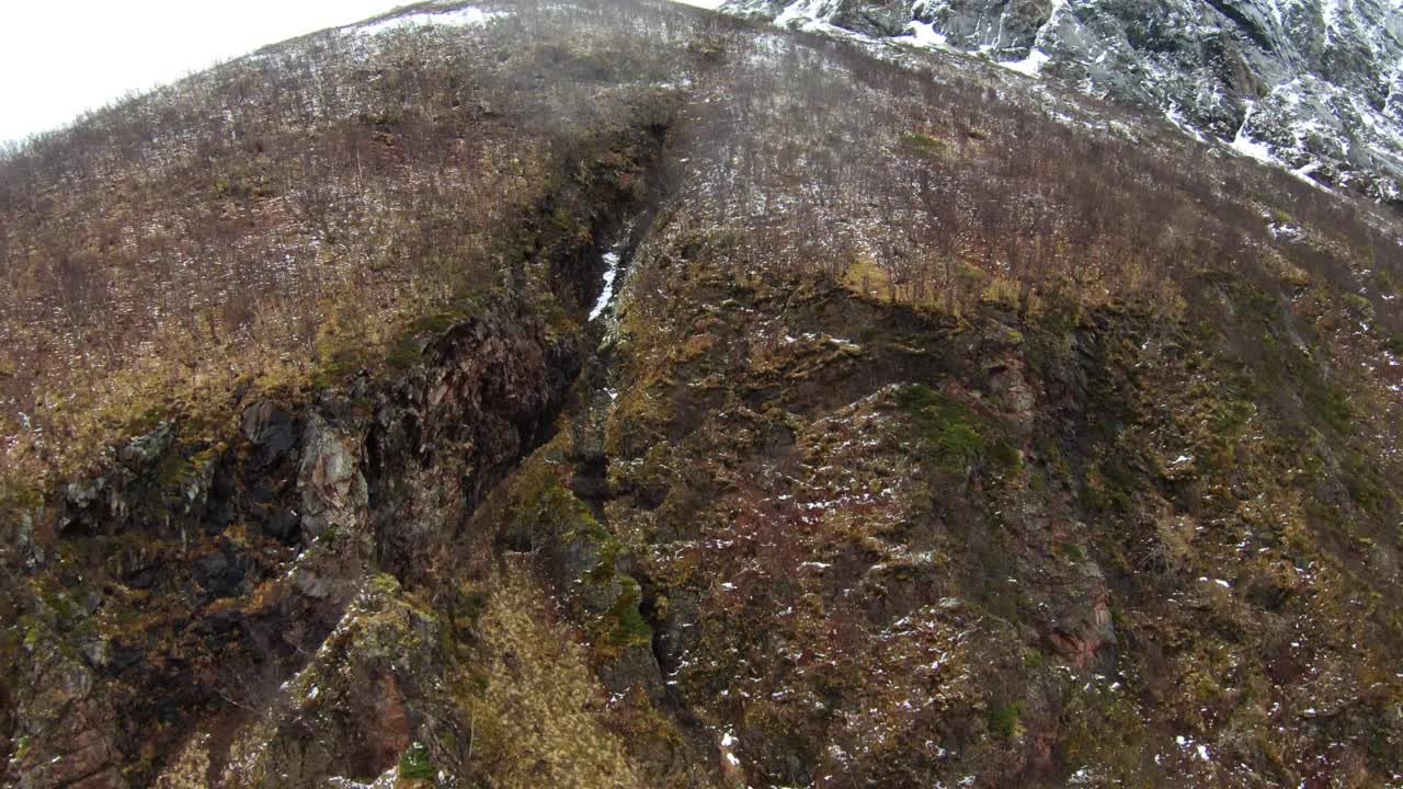 挪威特罗姆瑟，多云天空下的宁静雪山的空中向前拍摄视频素材