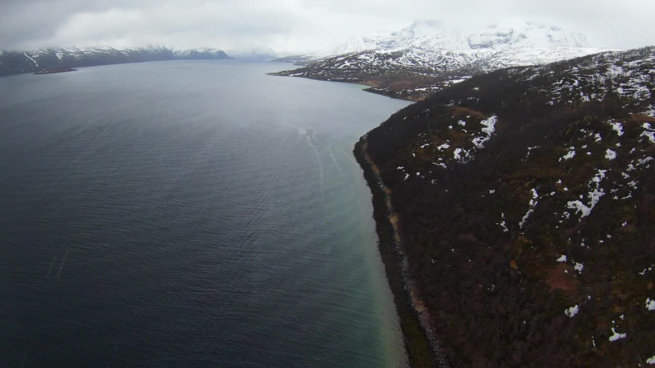 在云层下的雪山的空中风景，无人机向前飞行在海上-特罗姆瑟，挪威视频素材