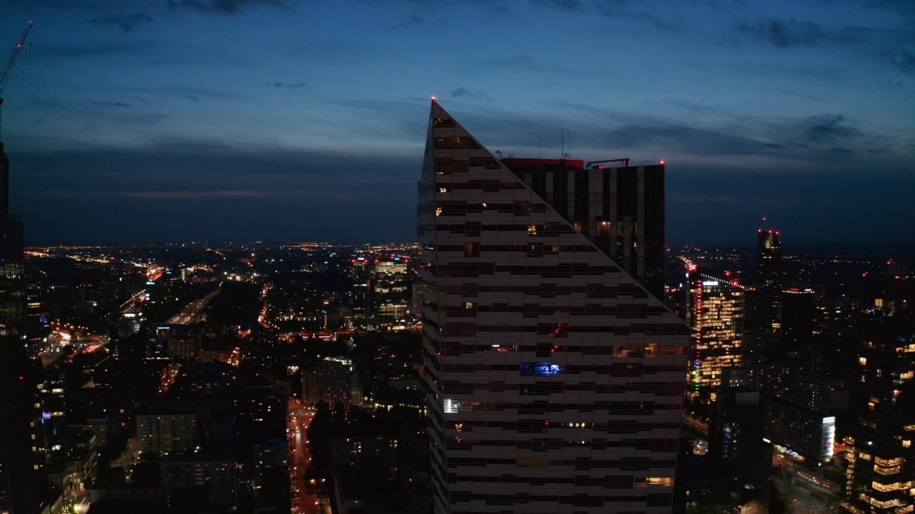 在光面玻璃幕墙的现代未来主义摩天大楼周围飞行。城市夜景全景。波兰华沙视频素材