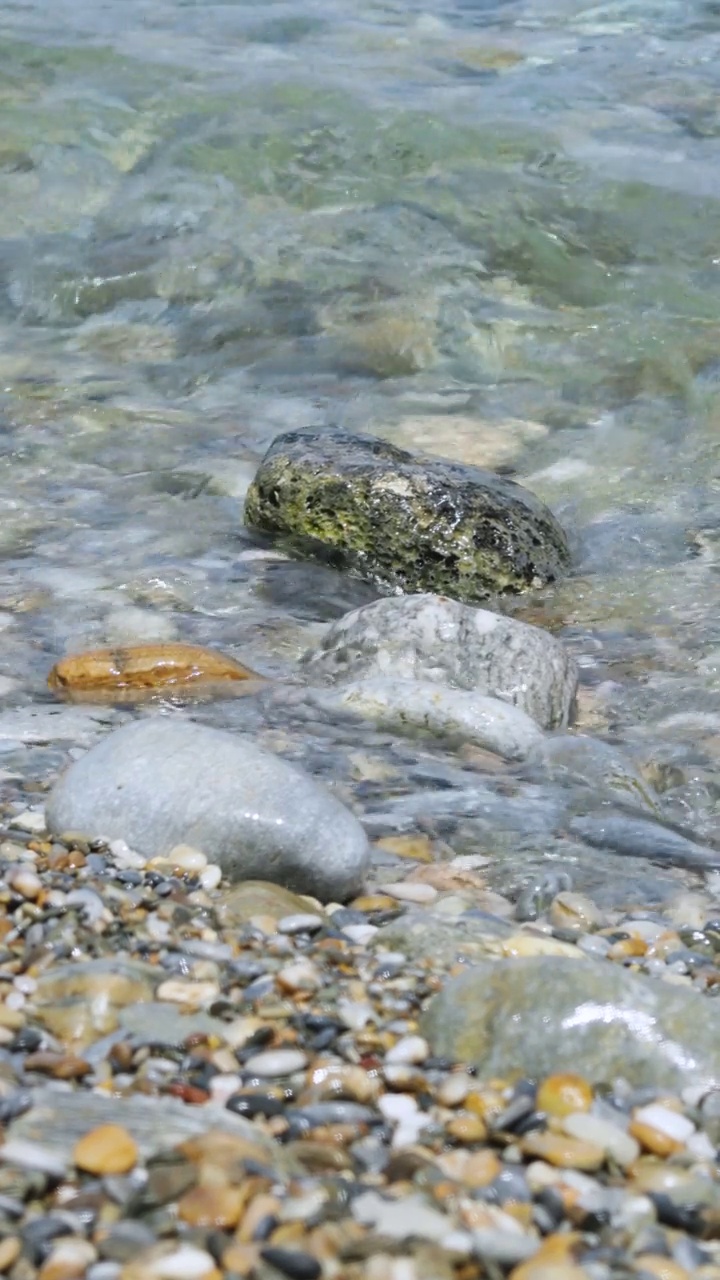 海浪和鹅卵石聚集在一起。海岸上的水花。海上度假的概念。垂直视频视频素材