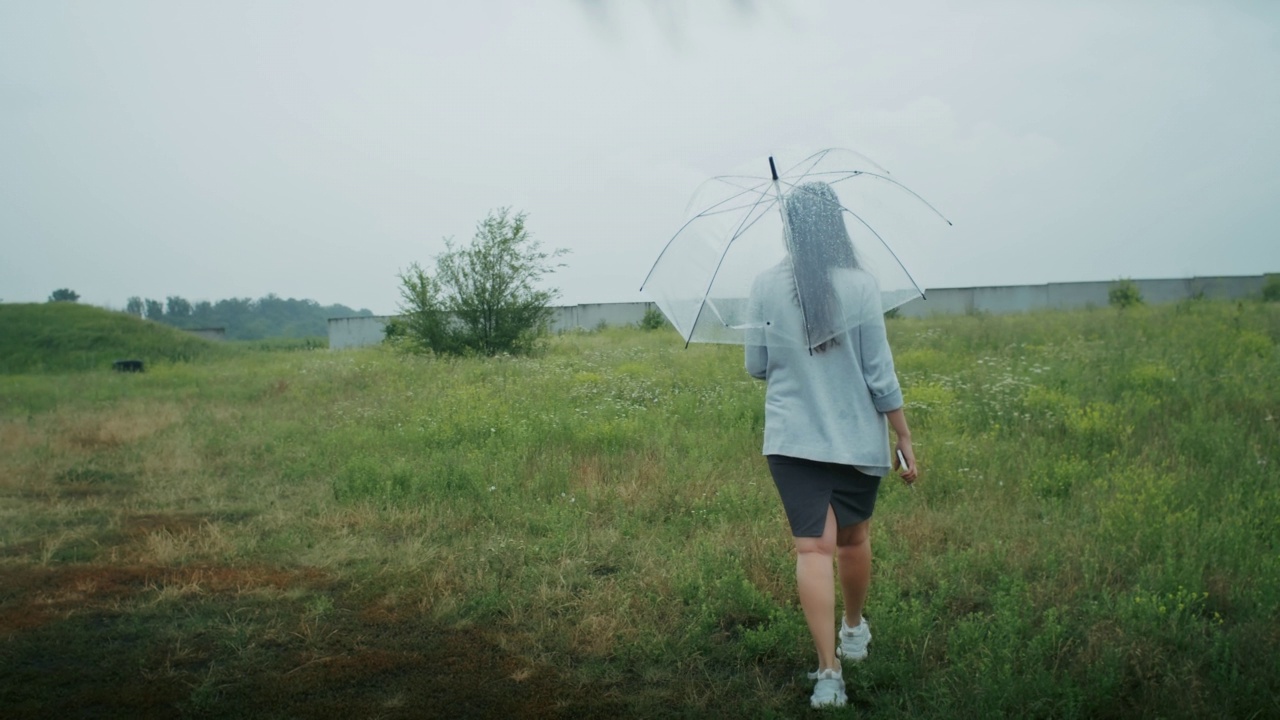 一个悲伤的亚美尼亚女人撑着伞在雨中行走。她喜欢这种天气。视频素材