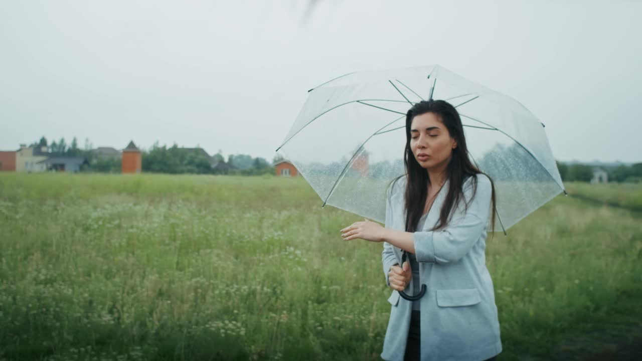 一个悲伤的亚美尼亚女人撑着伞在雨中行走。她喜欢这种天气。视频素材