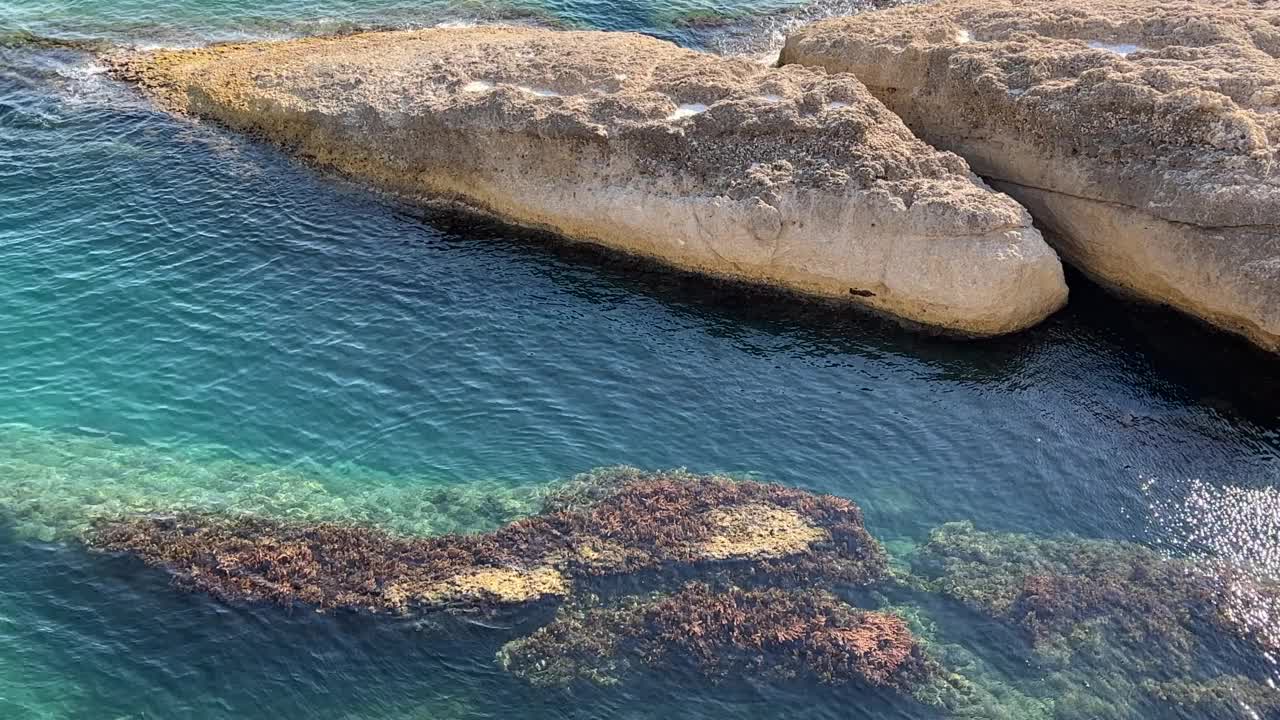 美丽的地中海岩石海岸的绿松石海景。闪闪发光的透明海水。海水表面的波浪在阳光下闪闪发光。视频素材