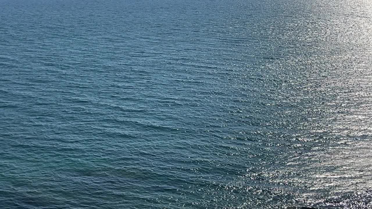 美丽的绿松石银色海景。波光粼粼的清澈海水。海水表面的波浪在阳光下闪闪发光。阳光照射在海浪上的刺眼光芒。视频素材