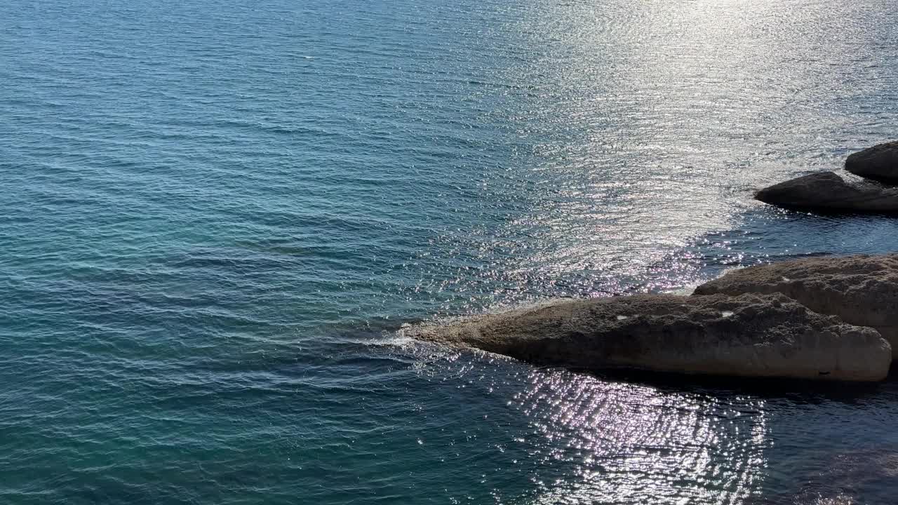 美丽的绿松石海景。波光粼粼的清澈海水。海水表面的波浪在阳光下闪闪发光。夕阳照射在海浪上的耀眼光芒。视频素材