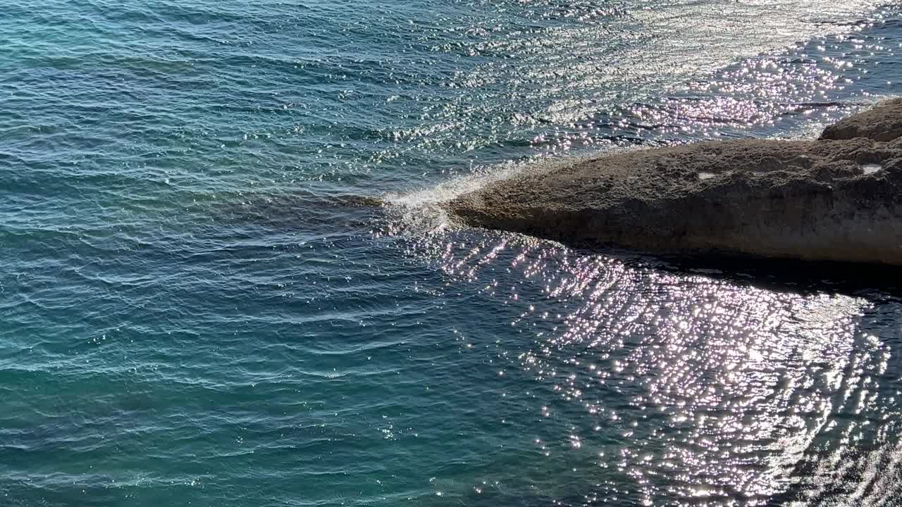 美丽的绿松石海景。波光粼粼的清澈海水。海水表面的波浪在阳光下闪闪发光。夕阳照射在海浪上的耀眼光芒。视频素材