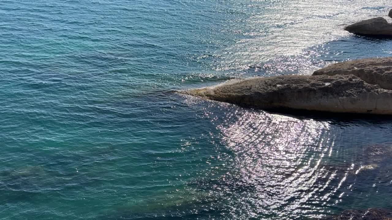 美丽的绿松石海景。波光粼粼的清澈海水。海水表面的波浪在阳光下闪闪发光。夕阳照射在海浪上的耀眼光芒。视频素材