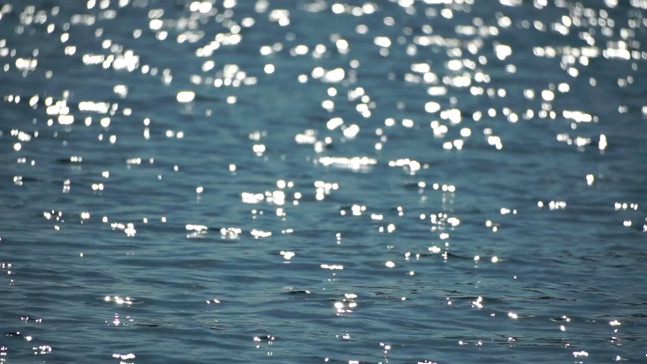 抽象海洋夏季海洋日落自然背景。小波浪水面上的运动模糊与金色的散景灯从太阳。度假、度假和休闲的概念。慢动作视频素材