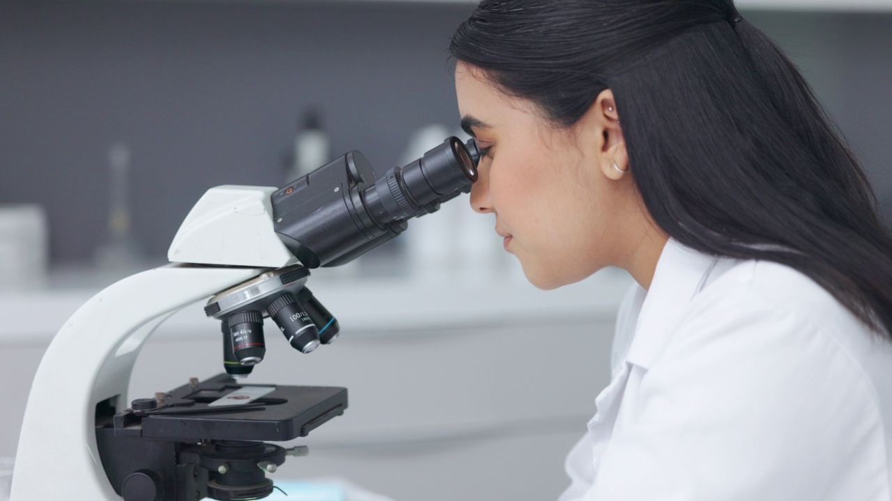 在研究实验室使用显微镜的女科学家。年轻的生物学家或生物技术研究人员使用最新的实验室技术设备工作和分析显微样本视频素材