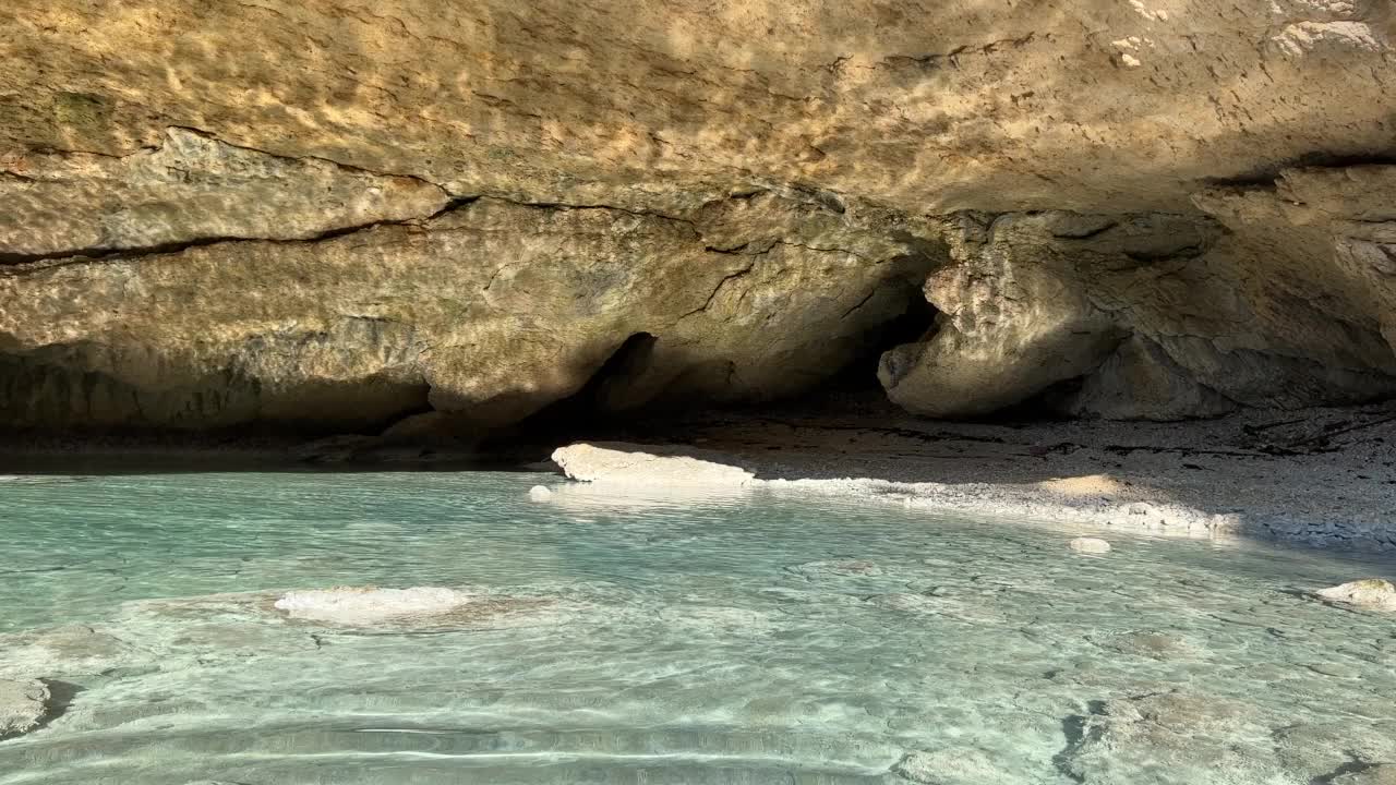 夏天，在海岛的海上有一个洞穴。鹅卵石在海床上。清澈平静的水面。地中海海岸的岩石和石头。视频素材