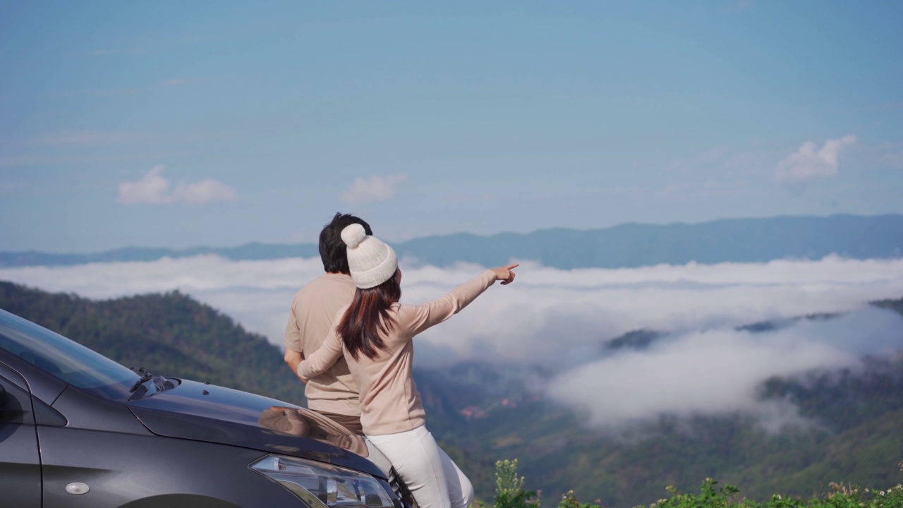 年轻夫妇旅行者与汽车看一个美丽的海雾山旅行，而驾驶公路旅行度假视频素材