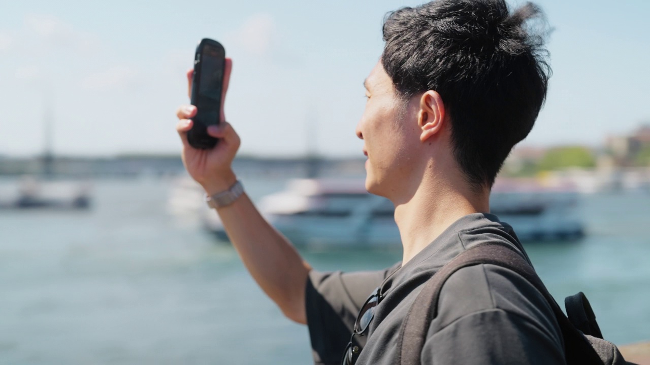 年轻的男性游客在他的旅行期间在城市中拍摄照片和视频视频素材