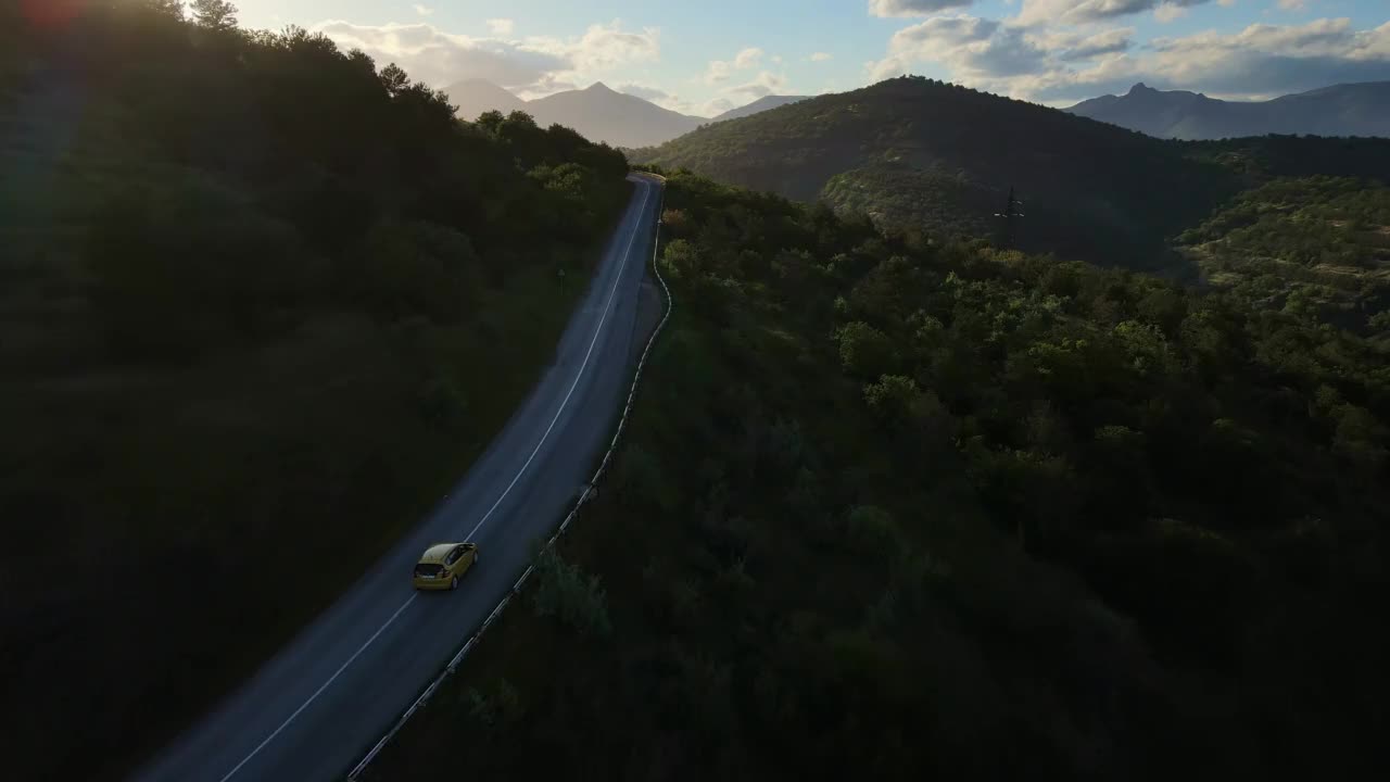 一辆汽车沿着蜿蜒的山路穿过山谷的鸟瞰图视频素材