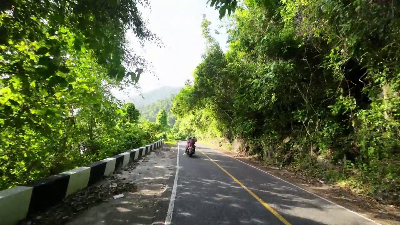 一辆摩托车由三个戴着头巾的妇女骑过Jalan Gunung Geurutee视频素材