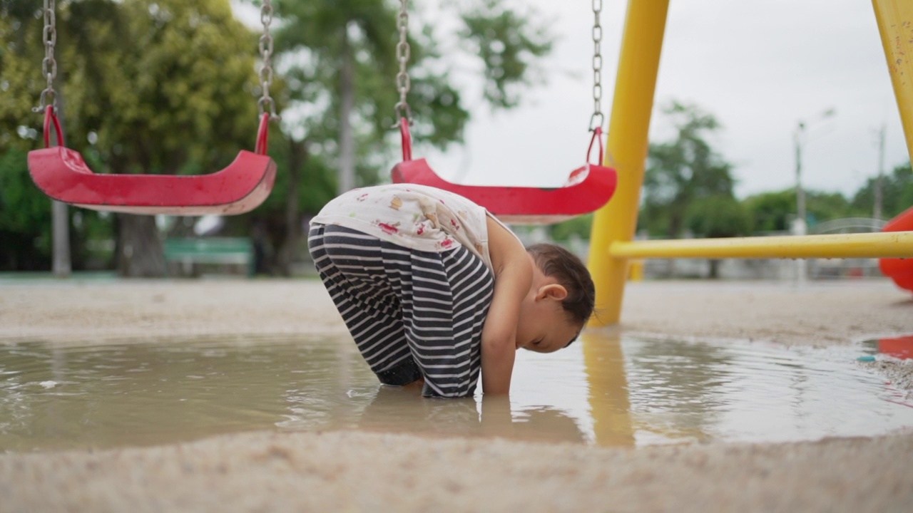 小男孩在水坑里玩，把头浸在水里。视频素材