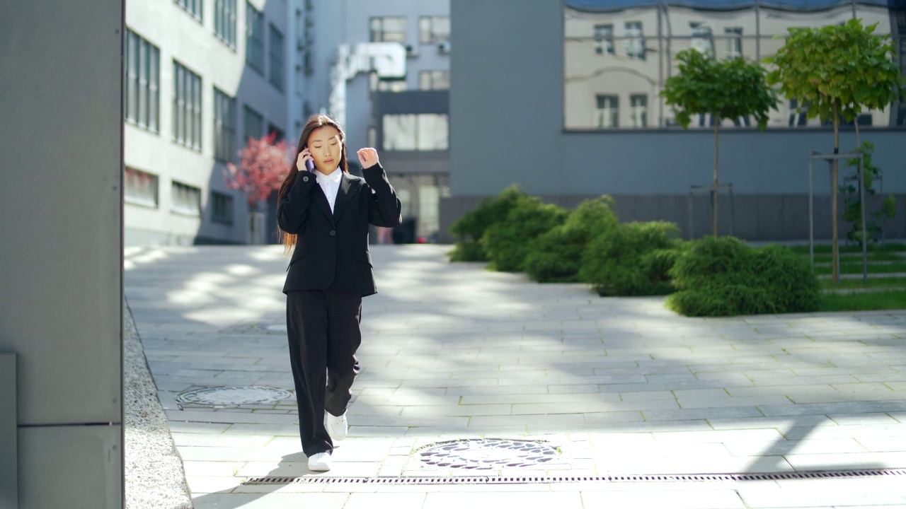 穿着西装的女商人或大学生走在城市的街道上，用手机聊天视频素材