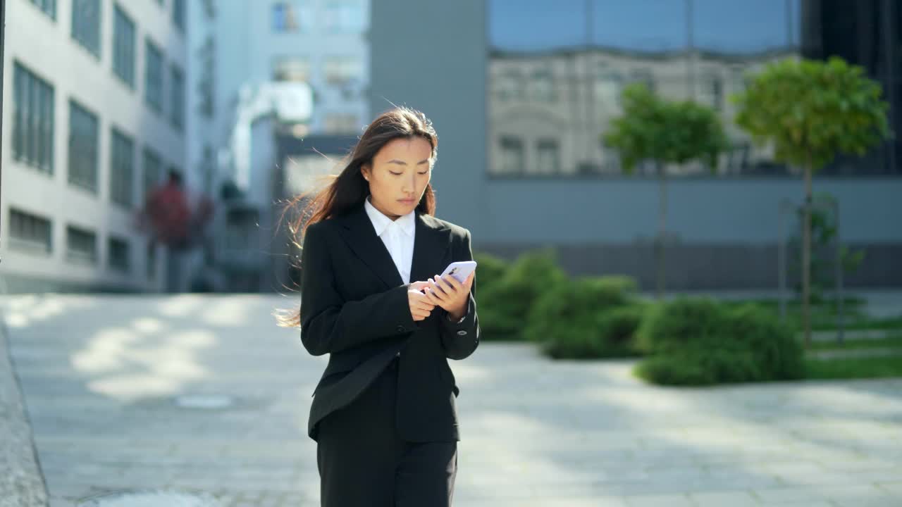 穿着西装的女商人或大学生走在城市的街道上，用手机聊天视频素材